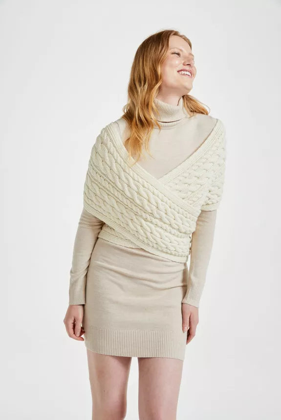 Vrouw draagt een beige jurk met daar overheen een gekruiste wikkel sjaal