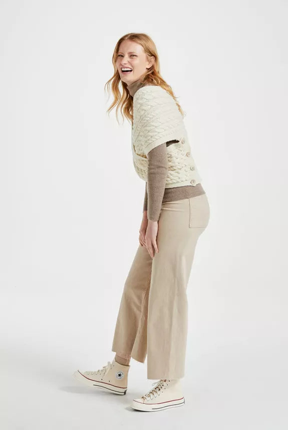 Een beige outfit met een gebreide wikkel sjaal. De sjaal sluit door middel van vier knopen.