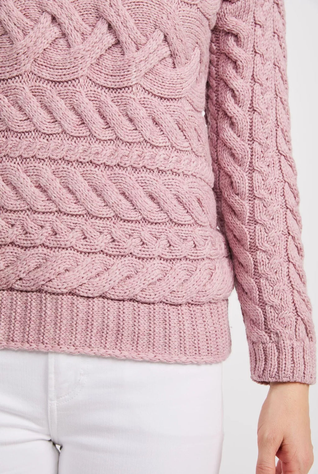 Close up beeld van een roze trui met horizontaal gebreide kabels en boorden langs de mouw en zoom.