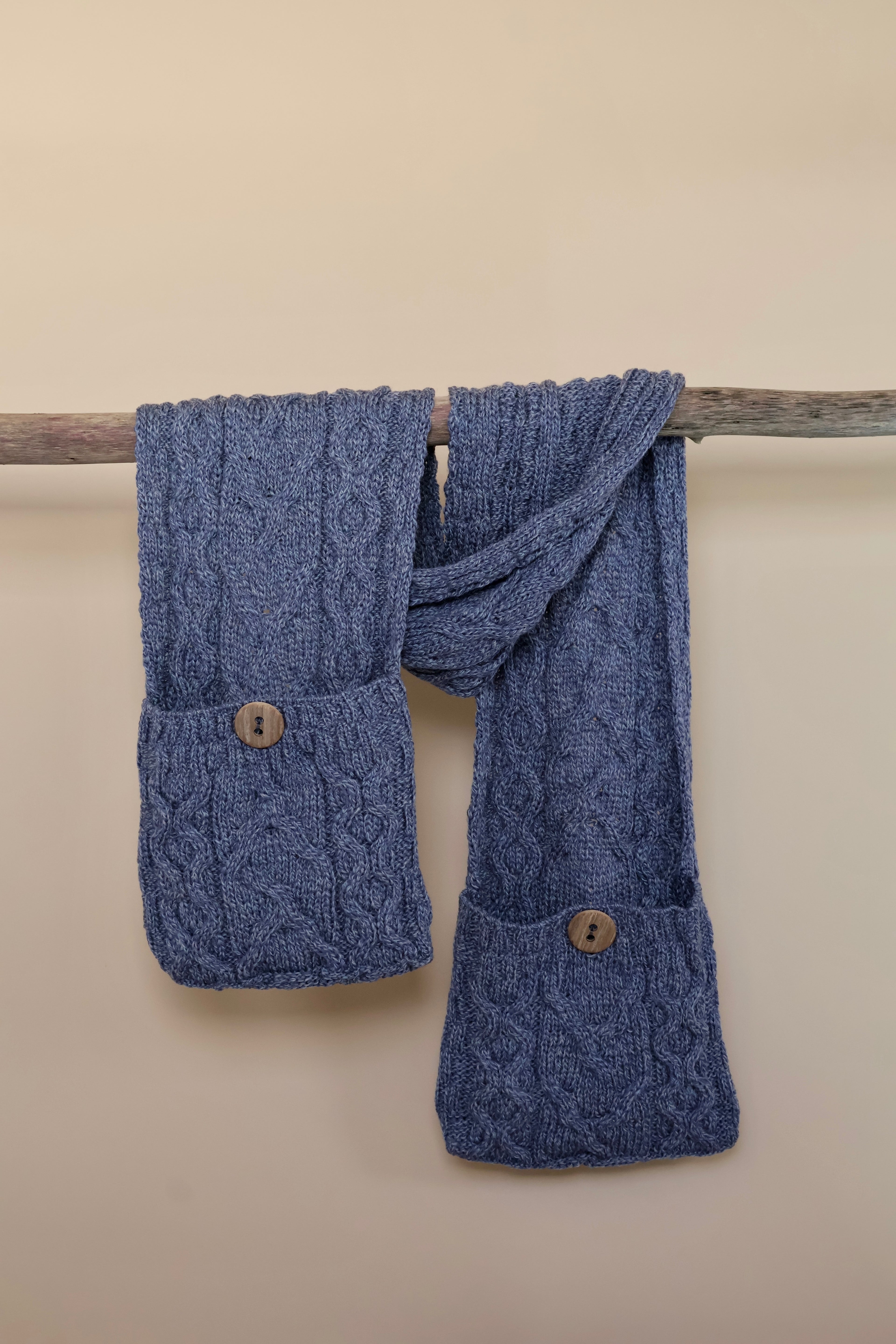 Grof gebreide sjaal met zakken welke gesloten worden door knopen.