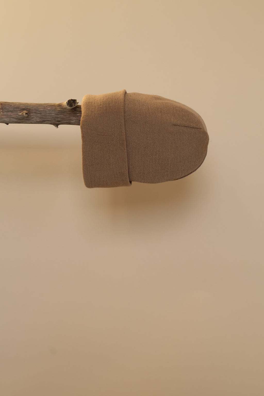 Camel kleurige muts gepresenteerd op een houten stok.