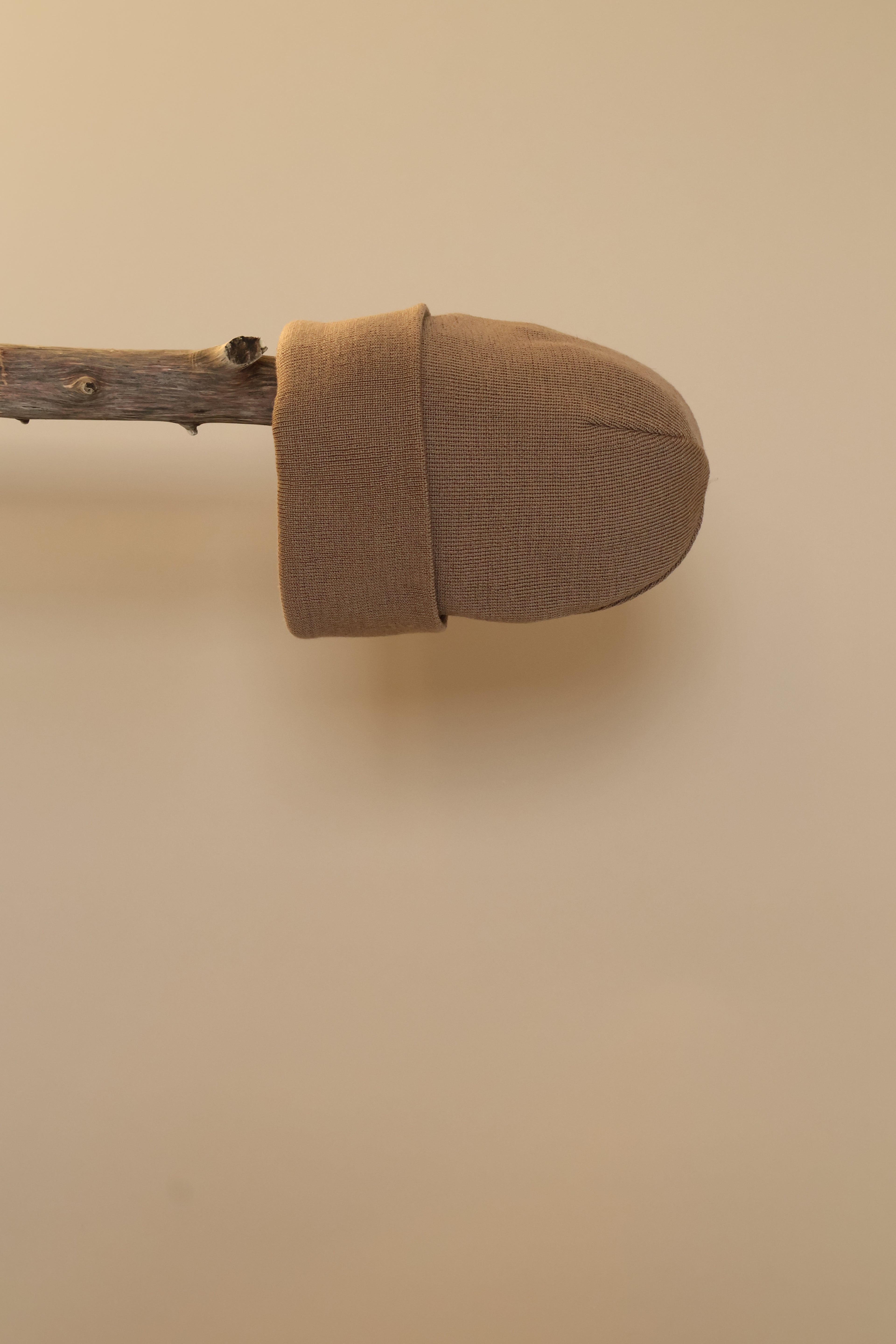 Camel kleurige muts gepresenteerd op een houten stok.