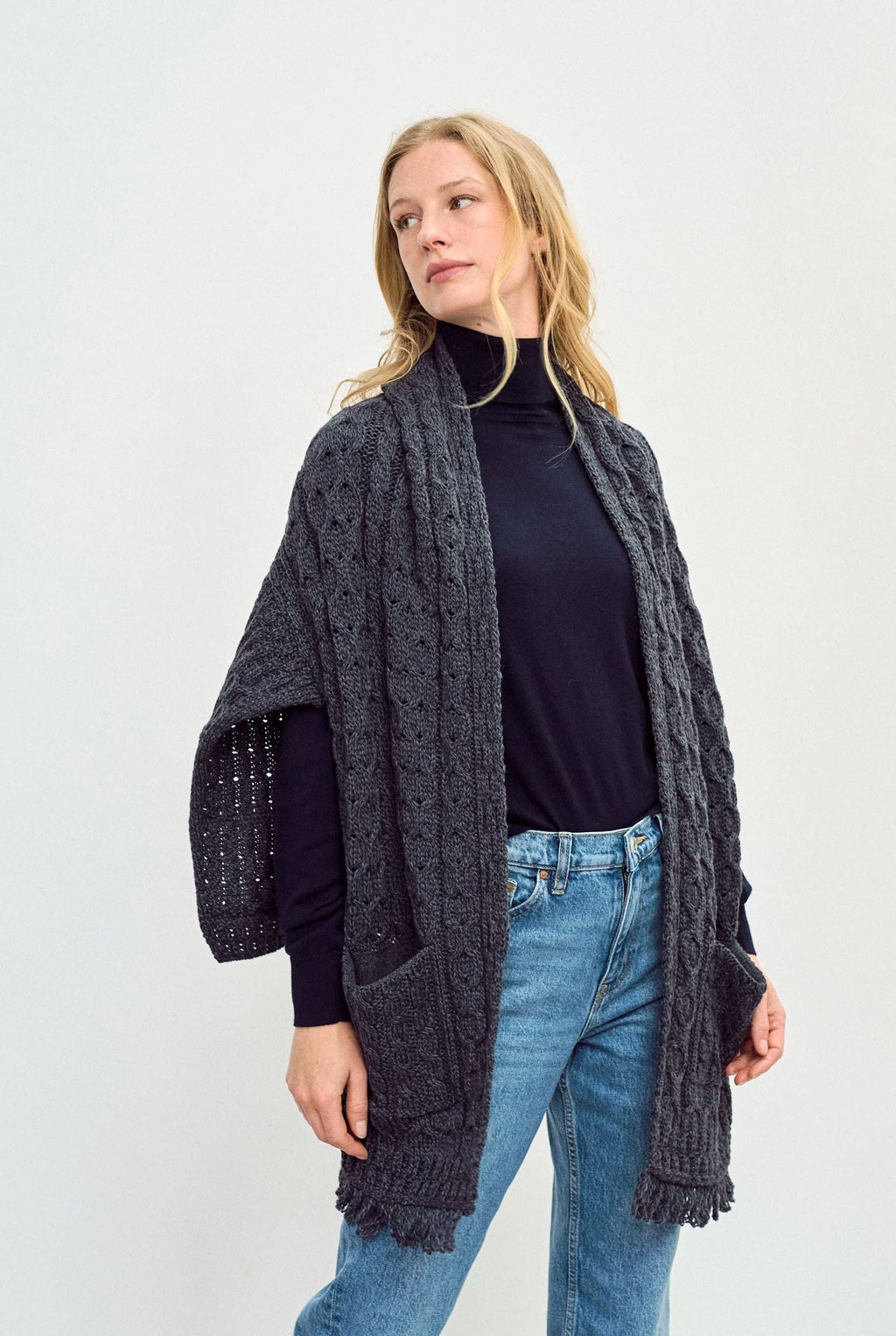 Een grijze omslagdoek met een lang achterpand en franjes.