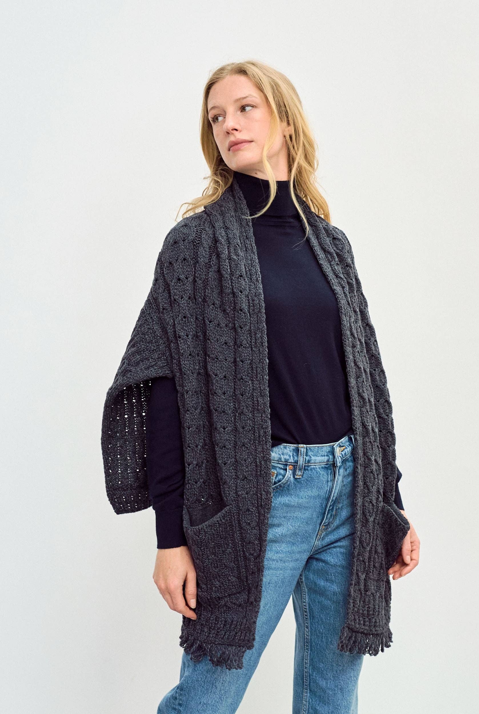 Een grijze omslagdoek met een lang achterpand en franjes.