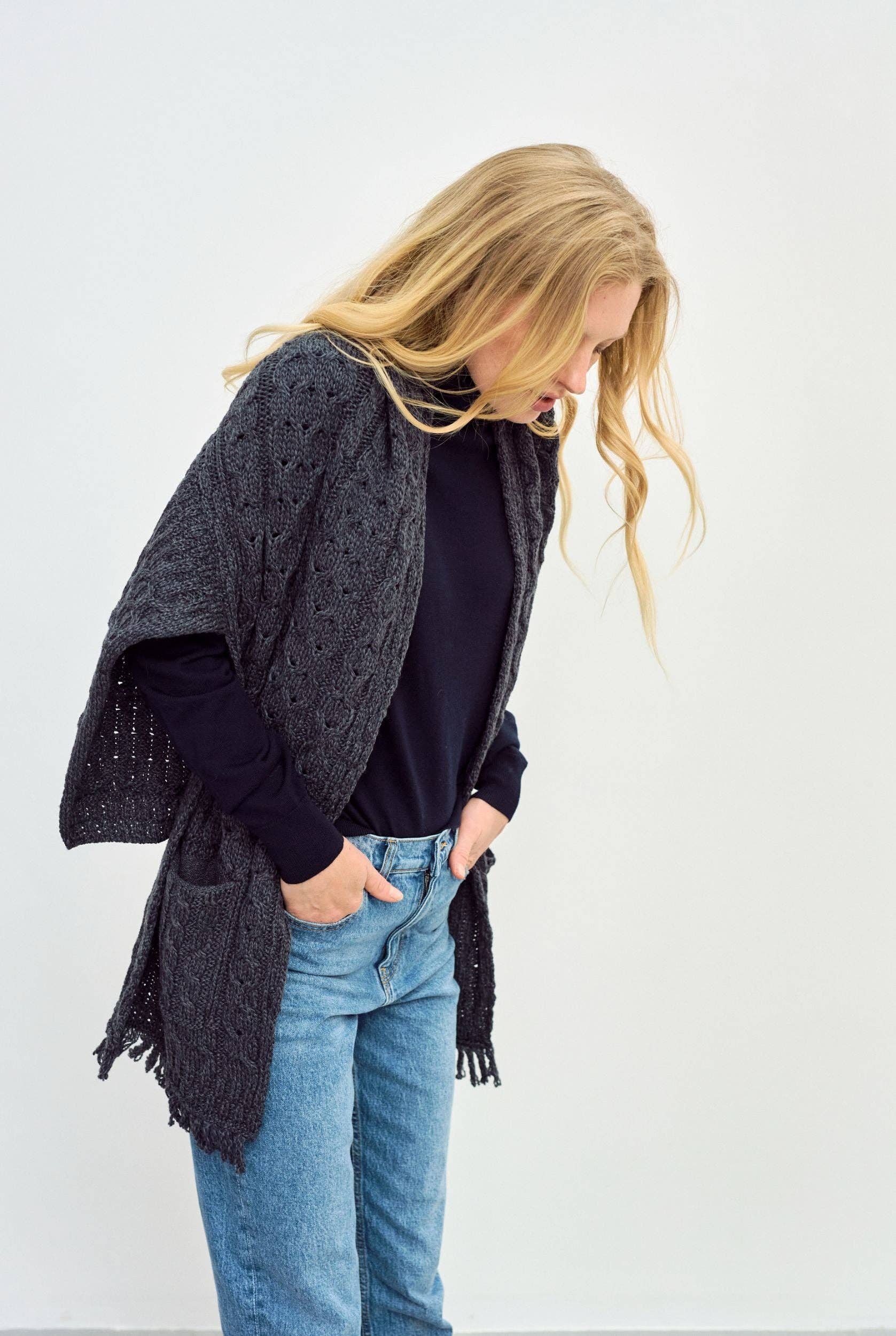 Zijaanzicht van een gebreide sjaal met zakken en franjes.