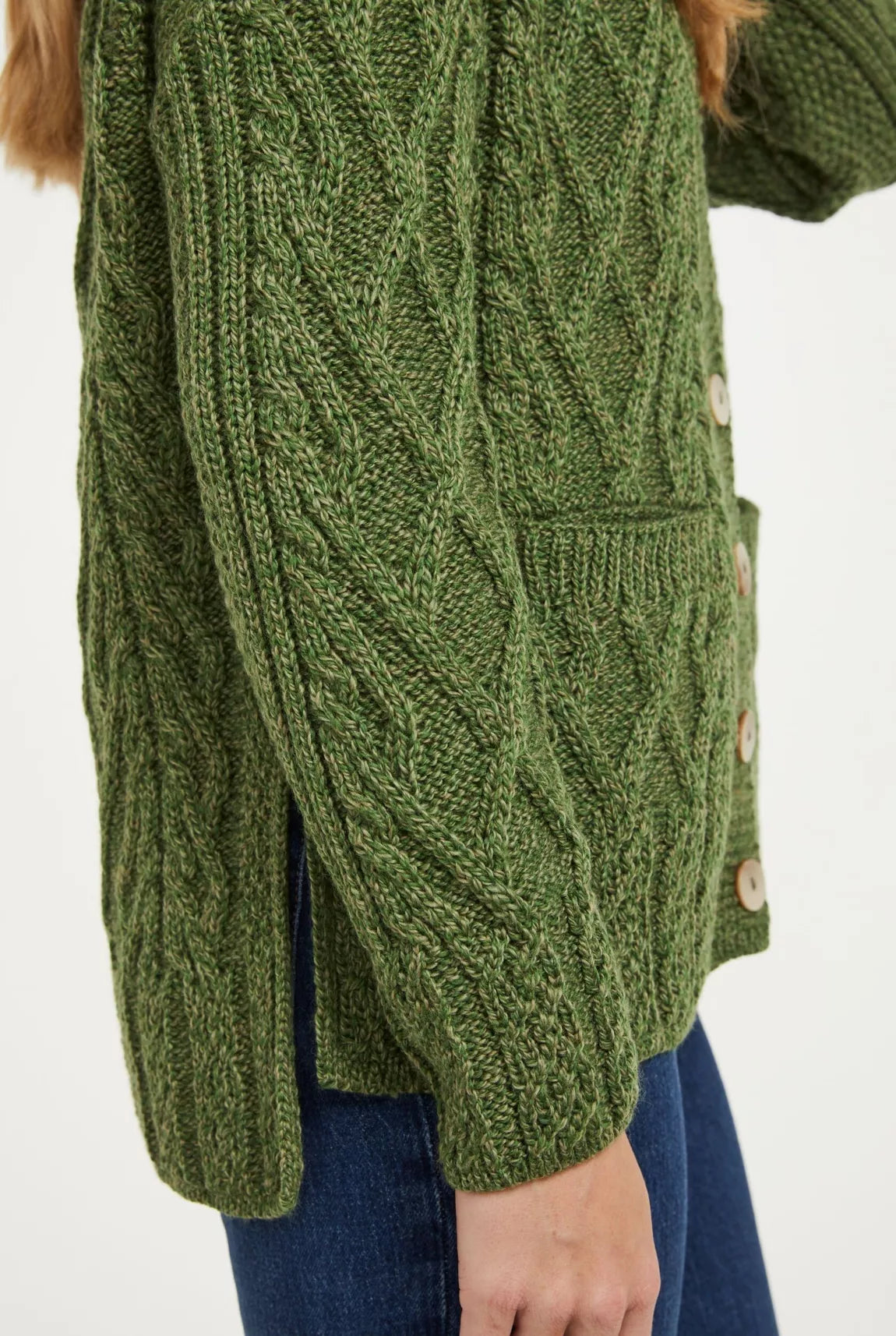 Close up beeld van het zijaanzicht van een groen vest waarin de nadruk ligt op de lengte verschil van het voor en achterpand en de split in de zijnaad