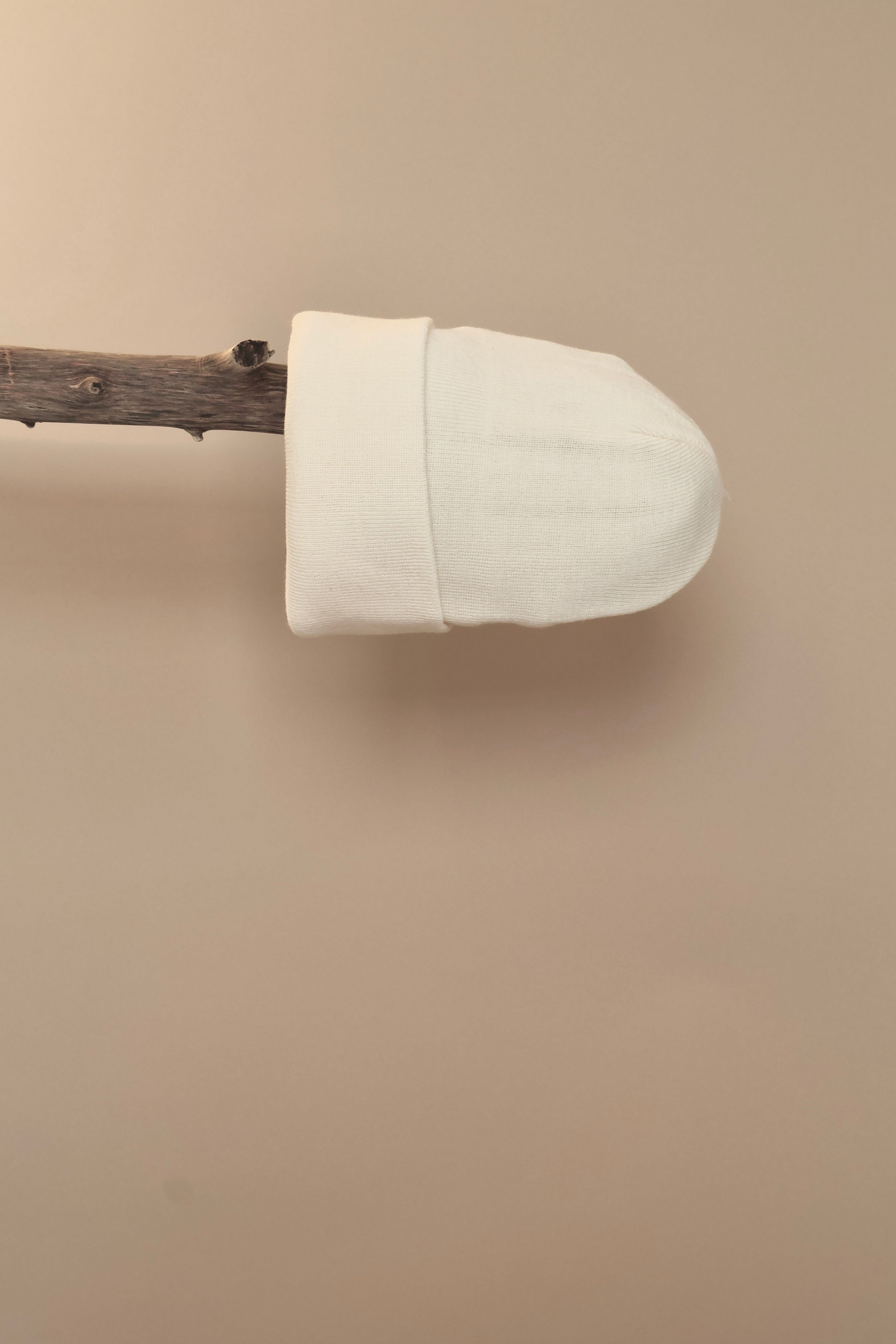 Witte gebreide muts gepresenteerd op een houten stok.
