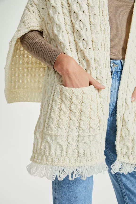 Close up foto van een vrouw met een witte sjaal. Ze heeft haar hand in de zakken op het voorpand om deze zakken te benadrukken. 